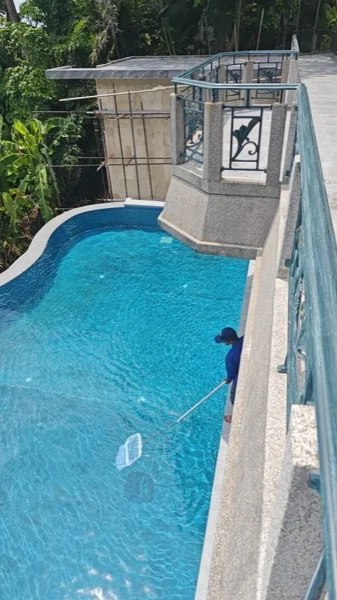 Our man skimming the pool after the surround was relaid, seen along the new walkway