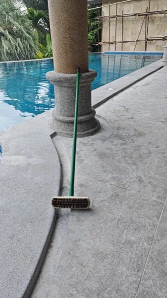 The relaid surround and pool coping in PebbleCrete Classic French Grey where they meet a column of the terrace