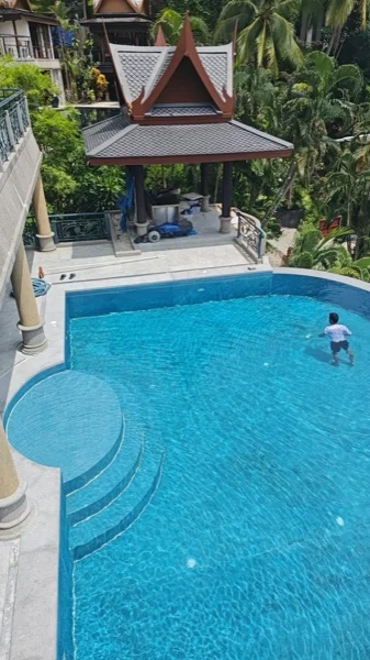 Cleaning the pool from the terrace above, with the relaid surround around it