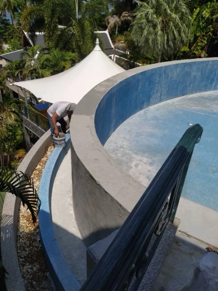 Fresh render going on the curved outer wall that carries the pool above the garden, before the Teal Pearl finish