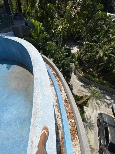 The failing walkway running along the top of the curved outer wall above the garden