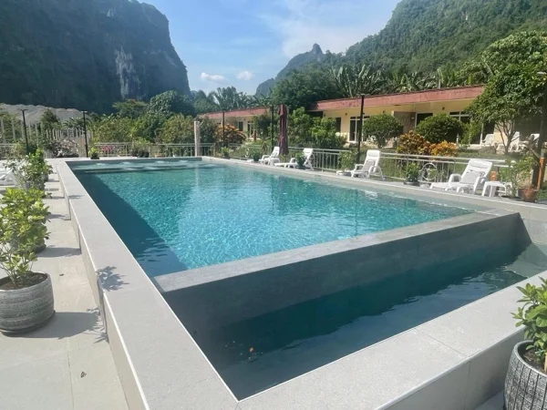 The finished resort pool in PebbleCrete Supreme Crystal Blue, the limestone karst of Phang Nga behind it