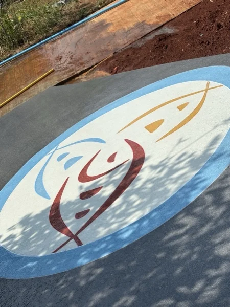 The laid logo at close range: the fish drawn in coloured aggregate against a pale ground