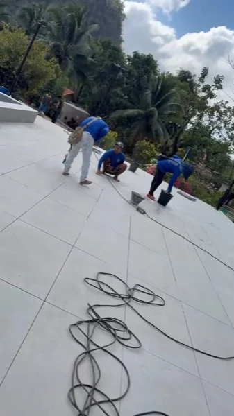 Our own crew grouting the large-format tiling of the terrace that runs around the pool: terrace work on the same site, not the pool finish