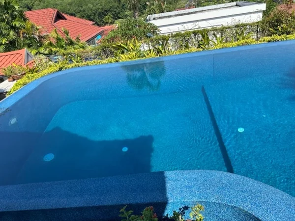 The corner of the pool where the water meets the raised spillway wall, both in Riviera Pearl