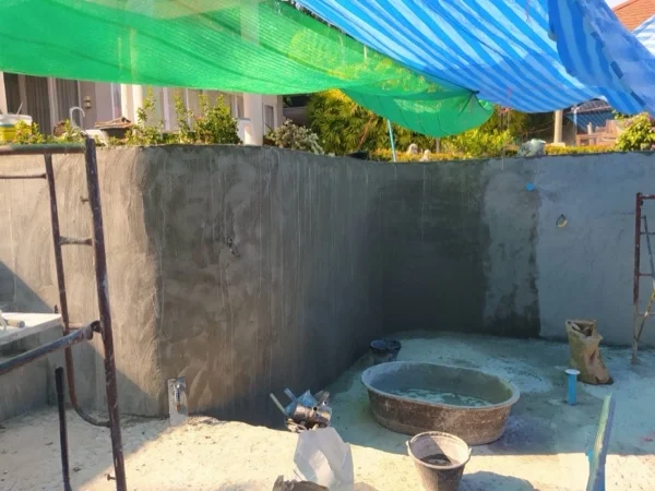 The rendered pool shell under shade cloth, waiting for the finish