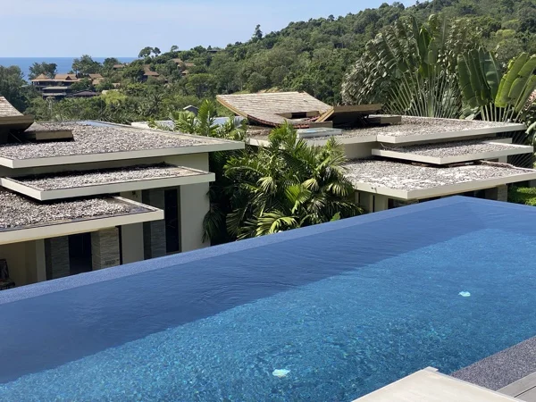 The overflow edge of the pool, Nightfall Pearl coping against Royal Blue water, with the hillside beyond