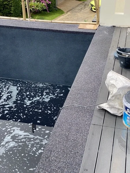 The finished pool being washed down before filling, with the Nightfall Pearl surround and the timber deck