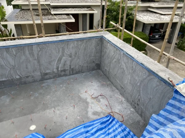 The rendered pool shell with its edge masked and screed pins set, ready for the finish