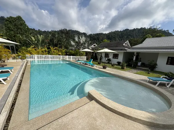 Villa Colina, Khao Lak — the renewed pool and its curved shallow ledge, with the guesthouse beyond
