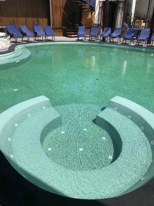 Curved jacuzzi seating in the PebbleCrete Classic Irish Green main pool at ZIMA Spa