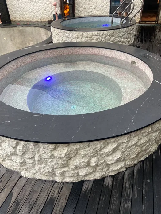 Contrasting (red glass beads for hot, blue glass beads for cold) PebbleCrete Supreme finishes in two circular plunge pools at ZIMA Spa